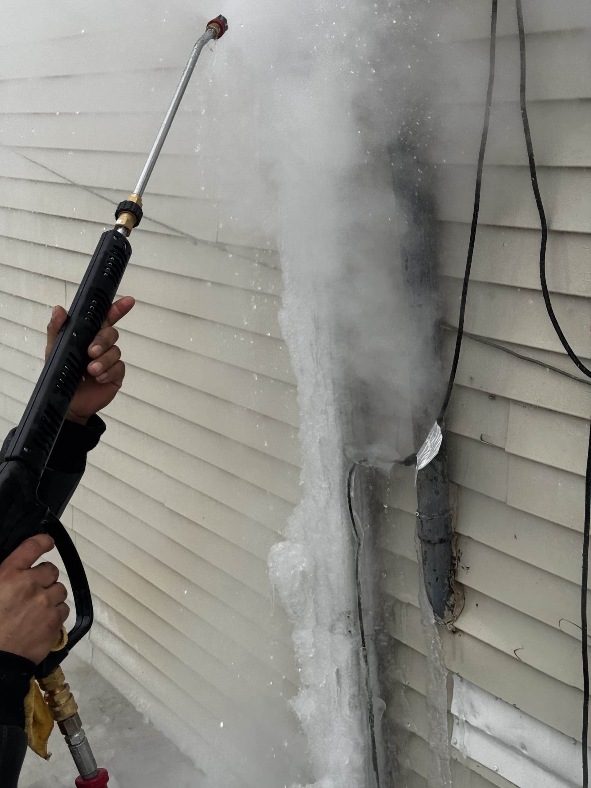 Ice dam removal from gutters and downspouts in Chicago using high-pressure steam equipment to melt ice and restore proper drainage